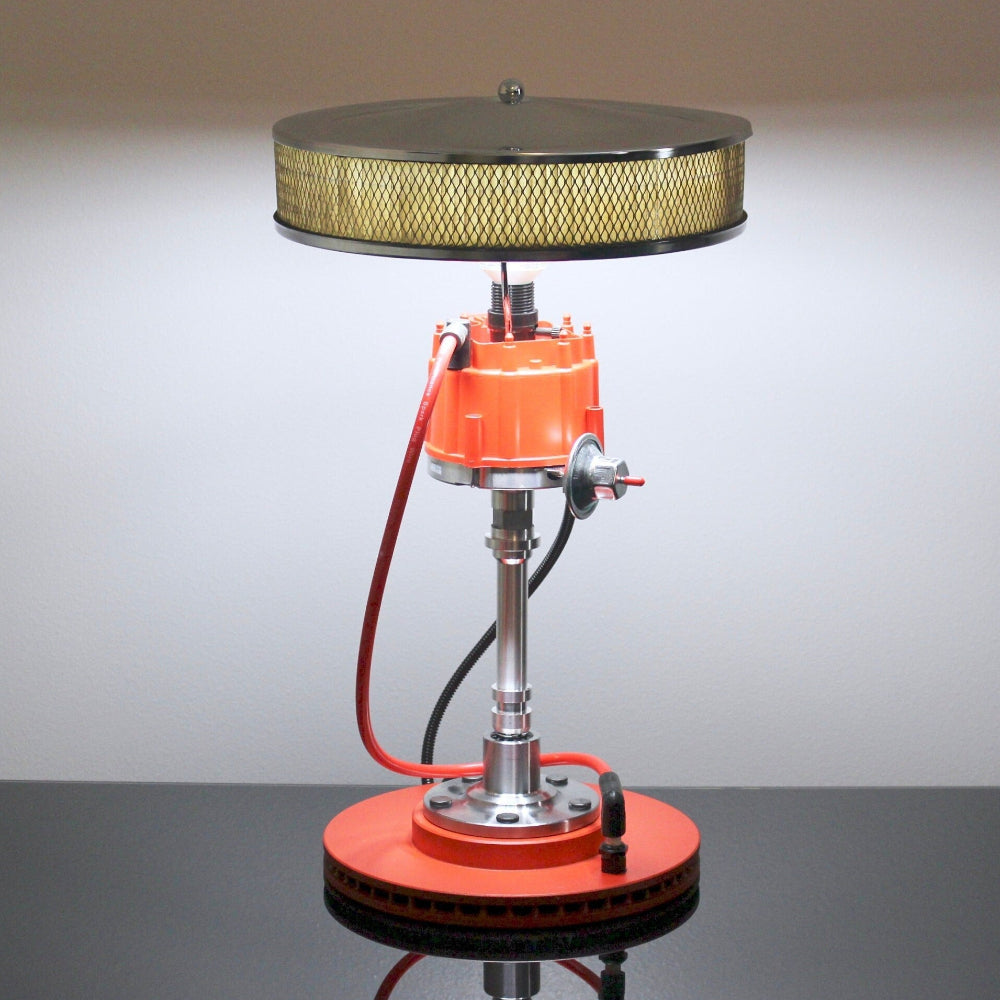 Vintage-style lamp with orange base and metal components on a reflective surface.