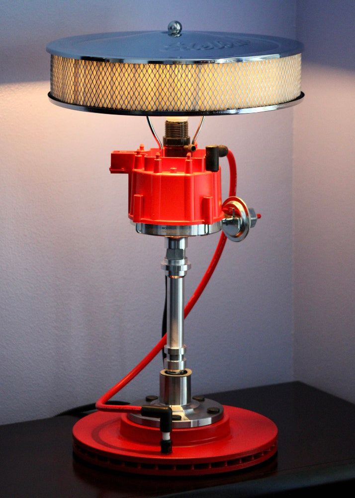 Red and silver industrial-style lamp on a dark surface with a neutral background