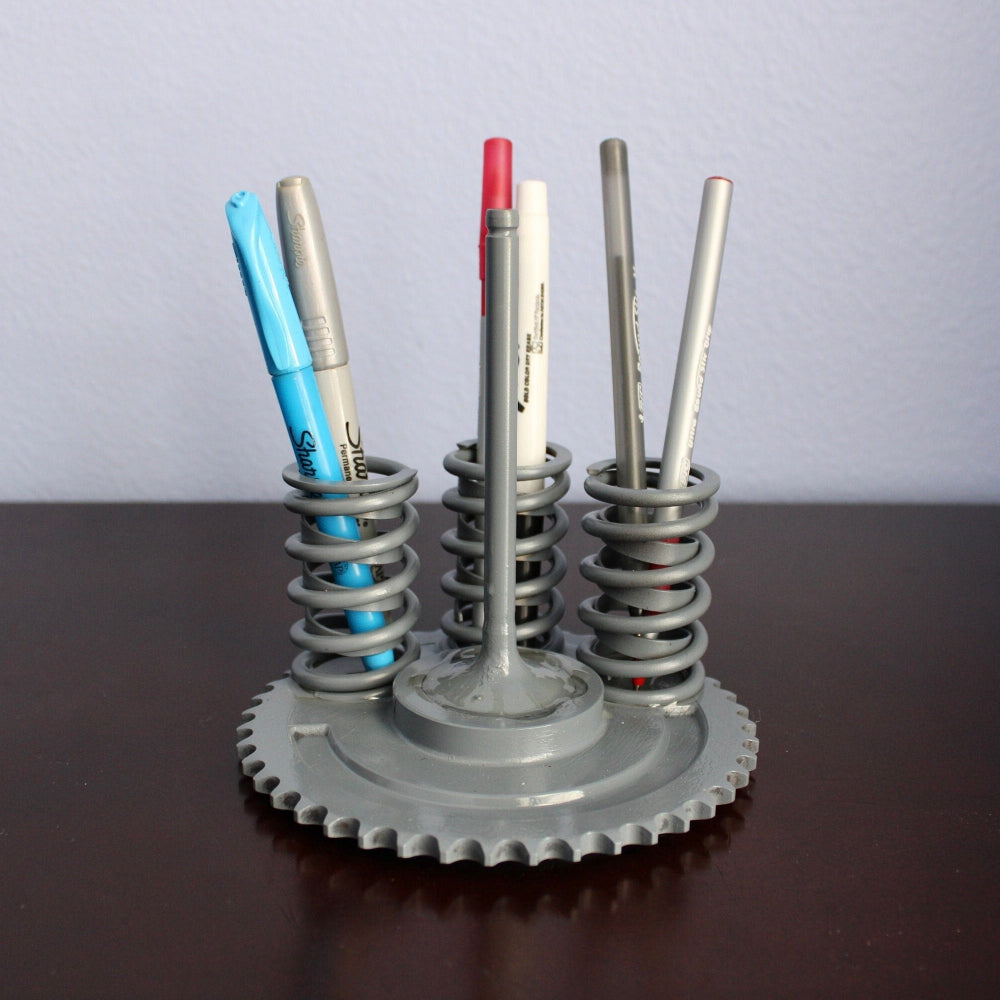 Pencil holder made from mechanical components on a wooden surface with a gray background