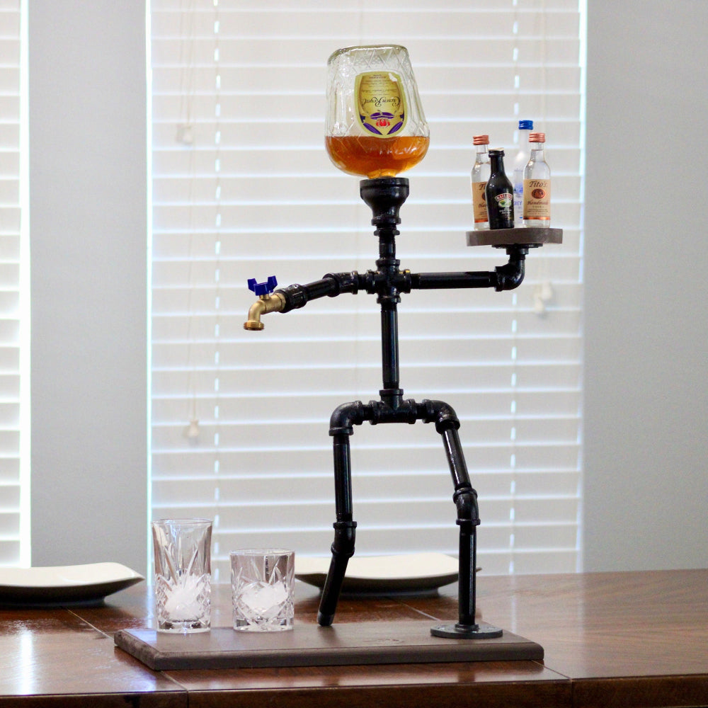 Decorative bottle holder shaped like a skeleton with a glass of beer on a wooden table.