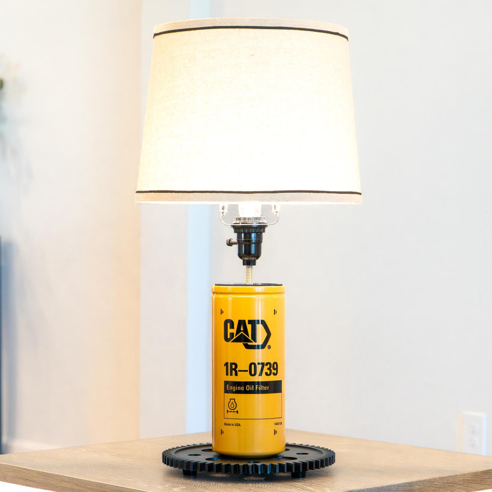 Yellow and black CAT oil filter lamp on a wooden surface with a lamp in the background
