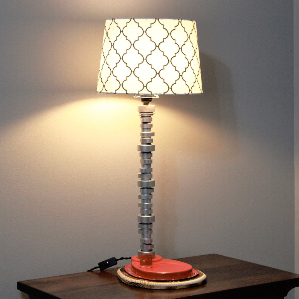 Decorative table lamp with a patterned shade on a wooden surface against a plain wall.