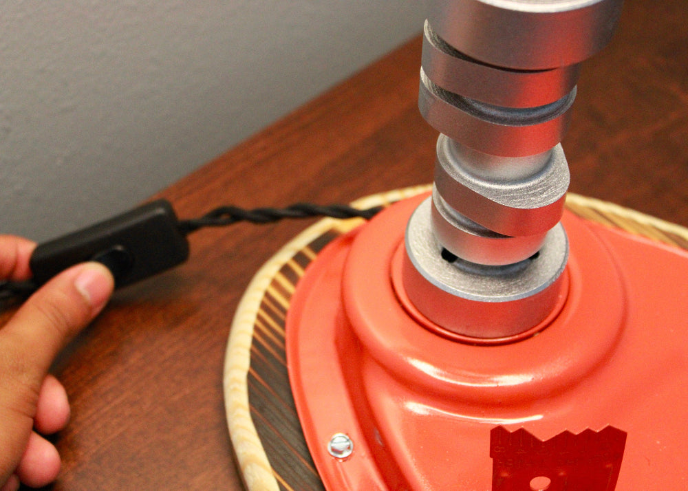 Red fire extinguisher with a black hose being connected on a wooden surface.