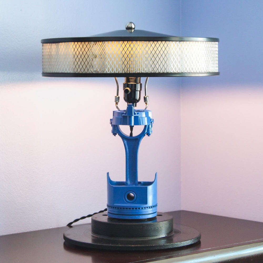 Table lamp with blue base and metallic shade on a dark surface