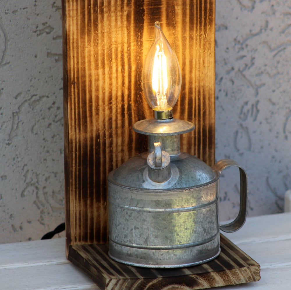 Vintage-style lamp with wooden base and metal container on a textured surface.
