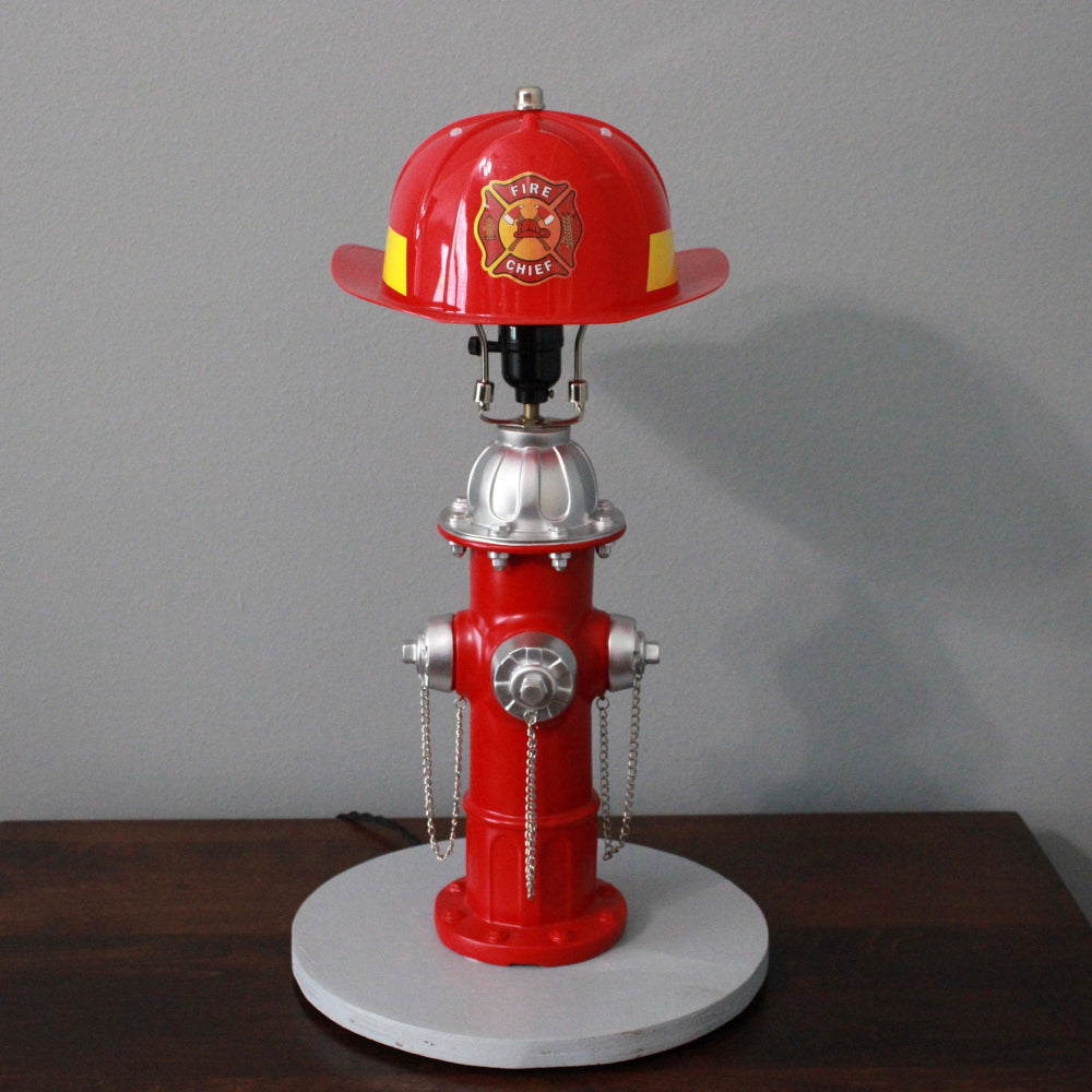 Red fire hydrant-shaped lamp with a helmet on a gray background