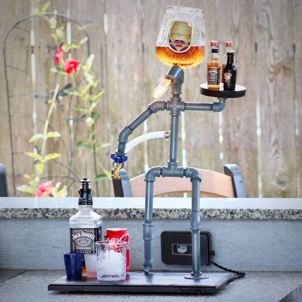 Bar setup with bottles and a glass on a metal stand outdoors.