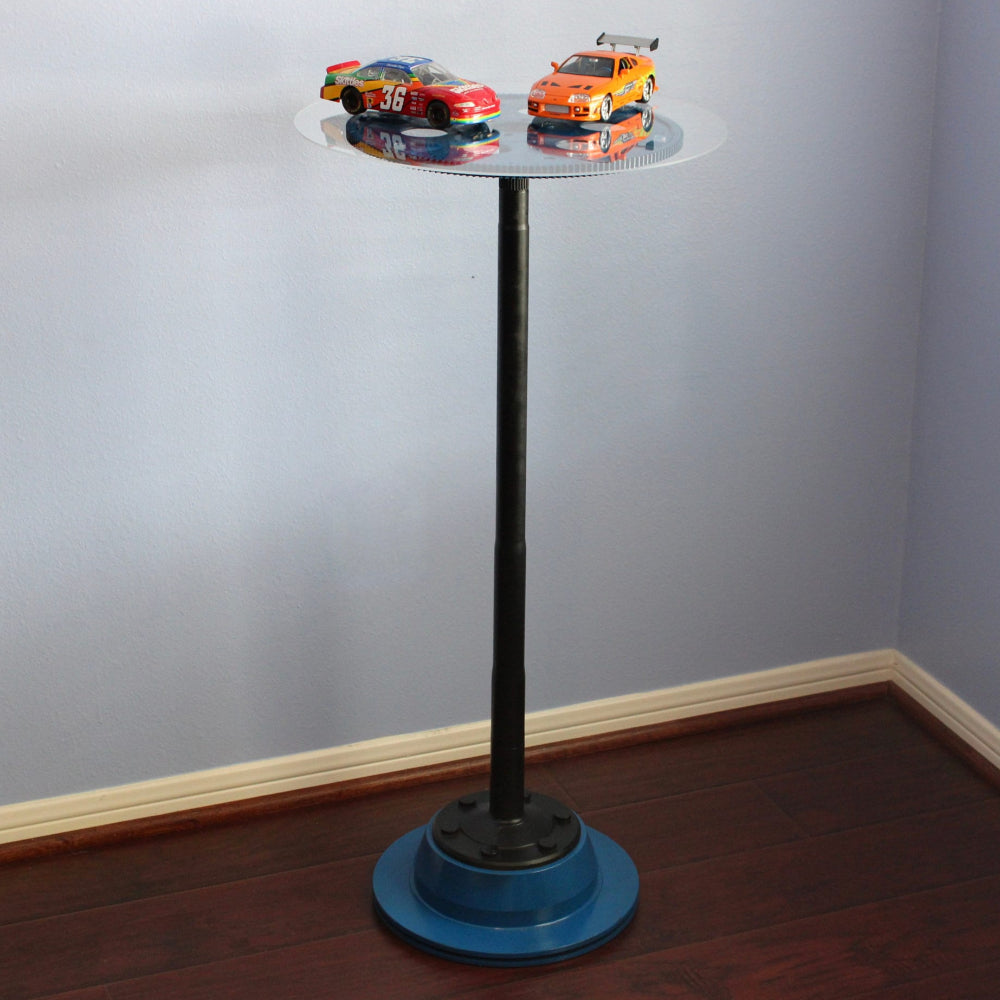 Small round table with toy cars on a plain wall background