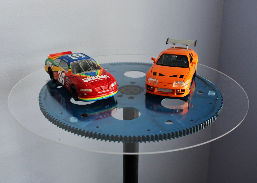 Two toy cars on a rotating platform with a plain background