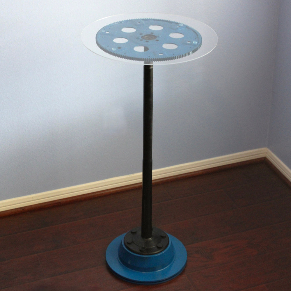 Blue and black industrial-style lamp on a wooden floor with a gray wall background