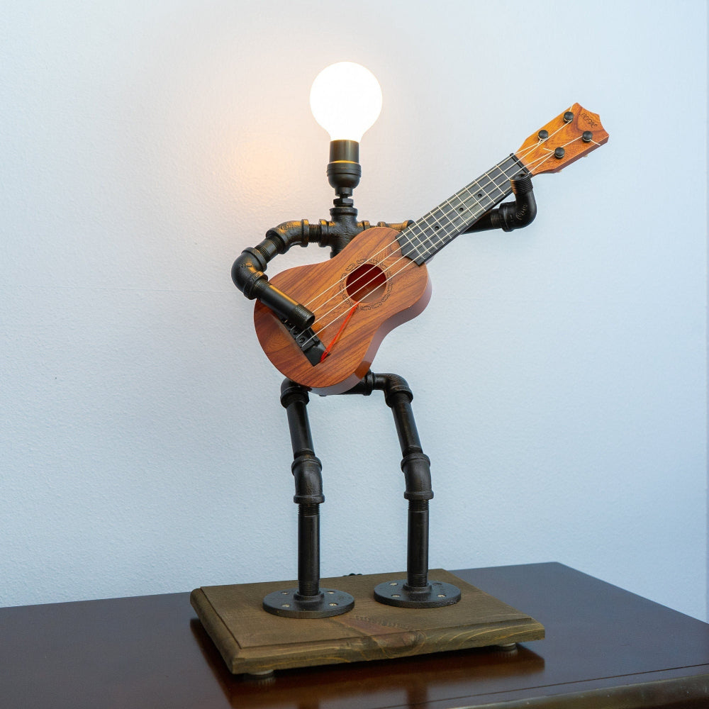 Ukulele-shaped lamp with metal stand on a wooden base against a light blue wall.