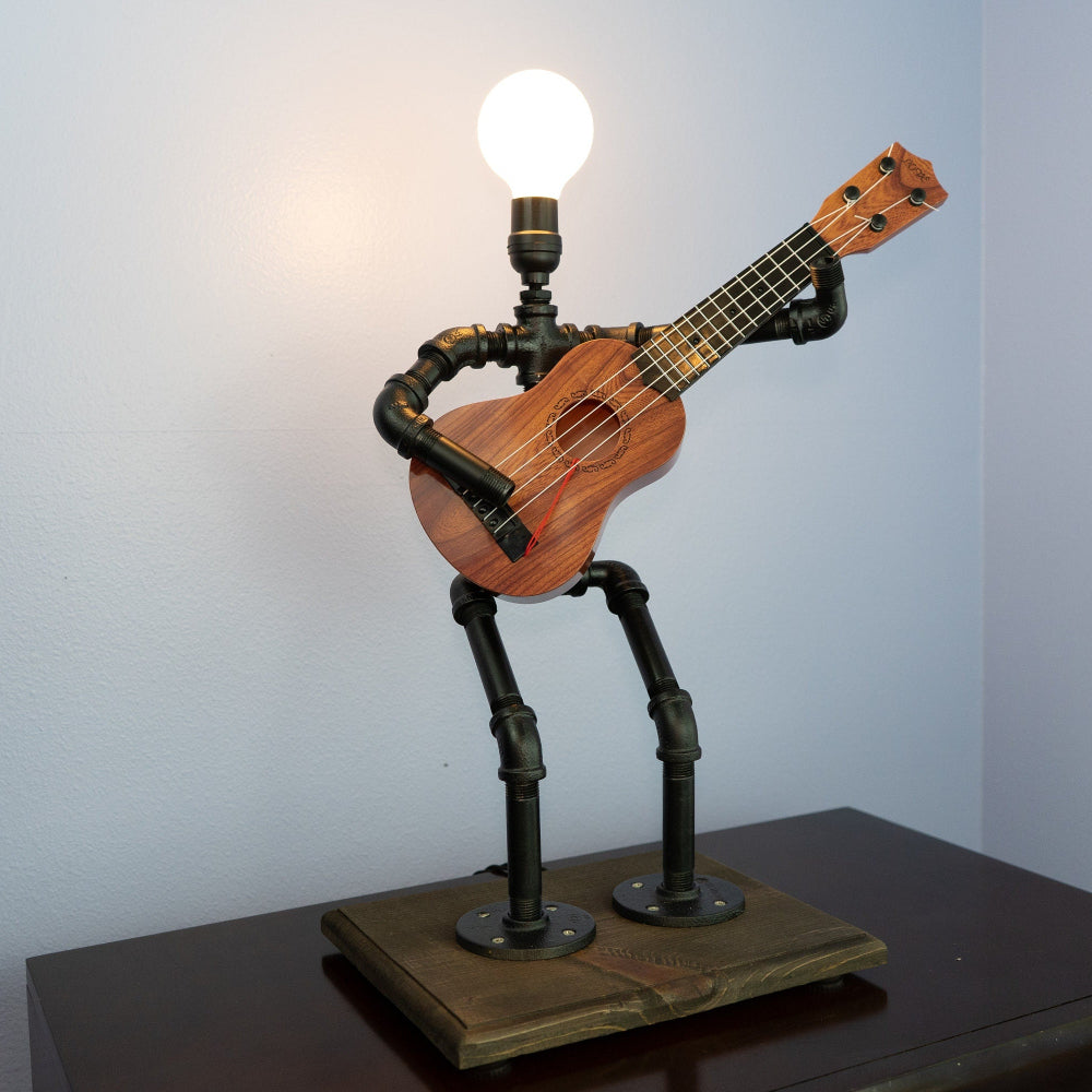 Guitar-shaped lamp with a light bulb on a stand against a plain background
