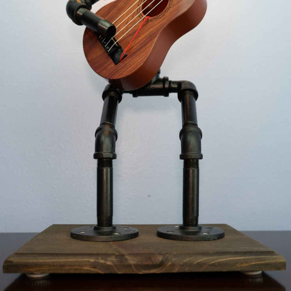 Wooden guitar on a stand made of metal pipes against a plain background
