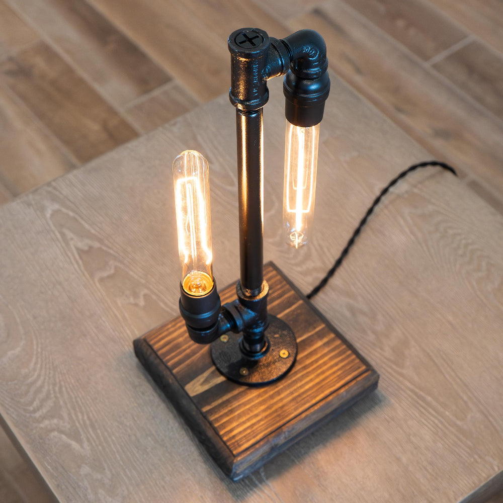 Table lamp with industrial design featuring wooden base and metal accents on a wooden surface.