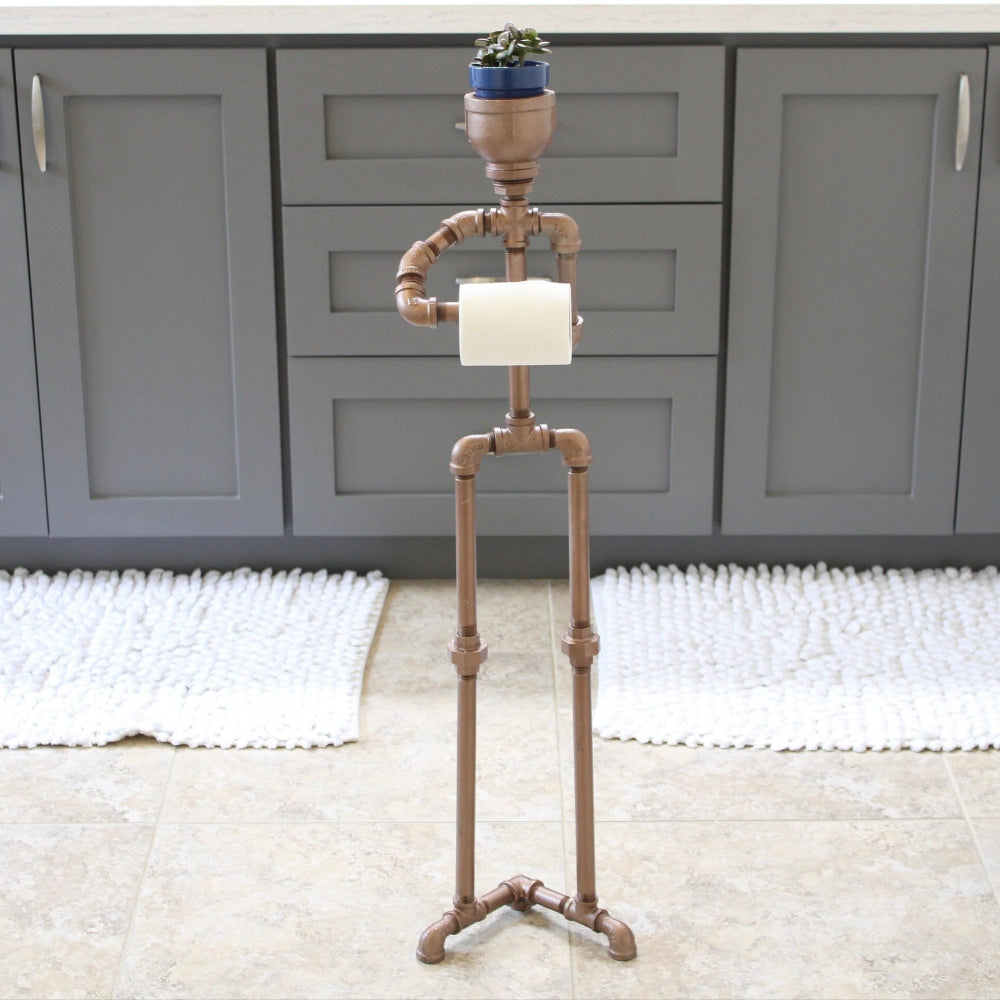 Decorative metal stand with a plant on top in a room with gray cabinets and a rug.