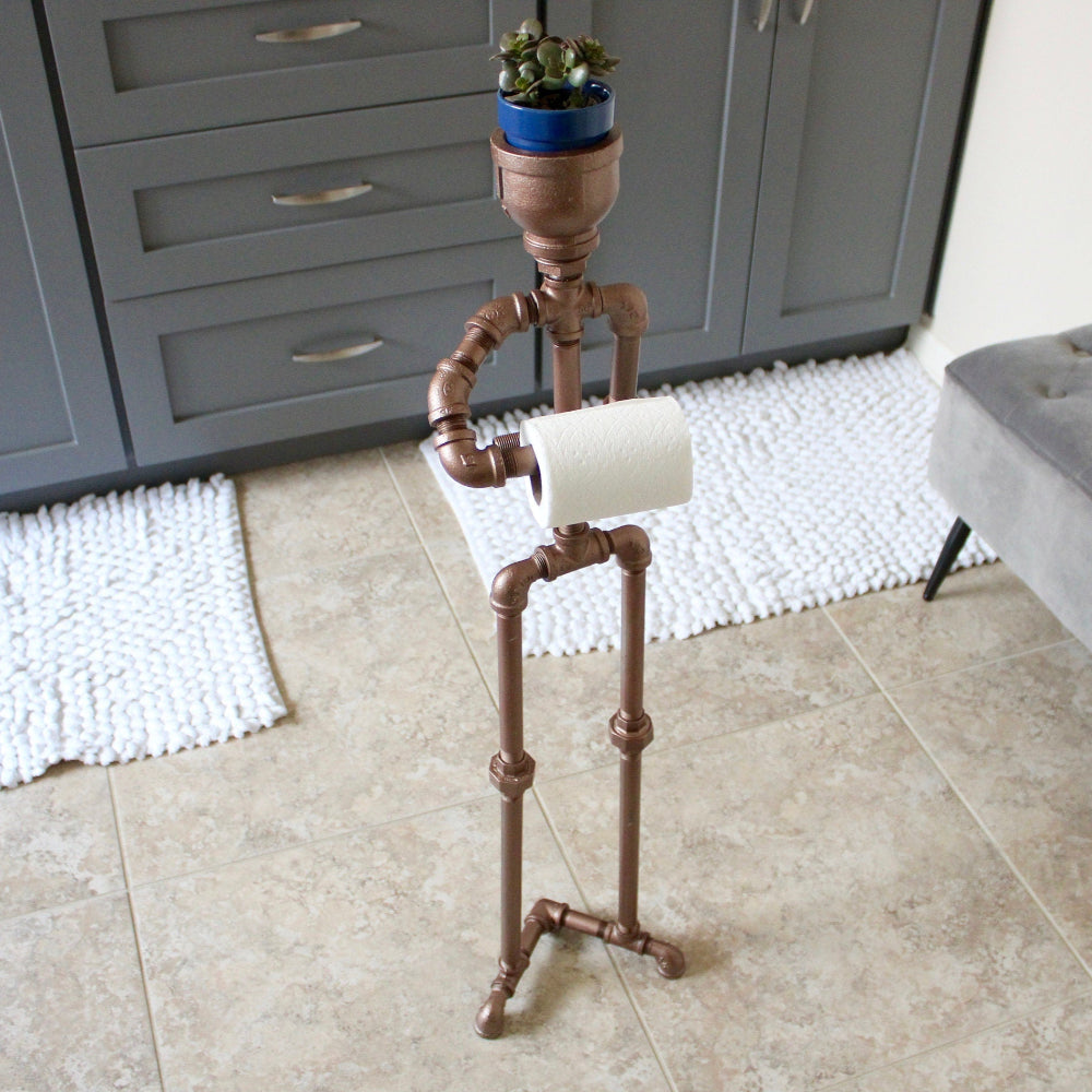 Decorative stand with a plant on a tiled floor next to gray cabinets and a bench.