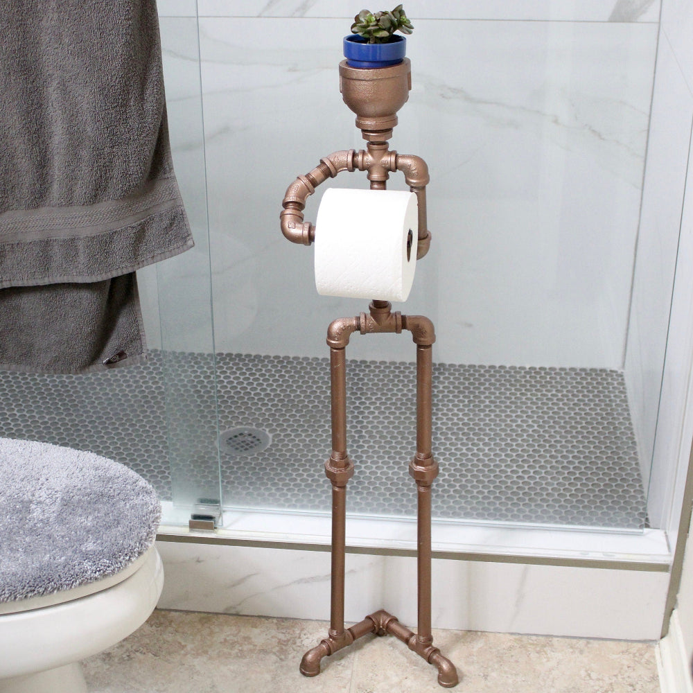 Bathroom with toilet paper holder made of copper pipes, towel, and plant.