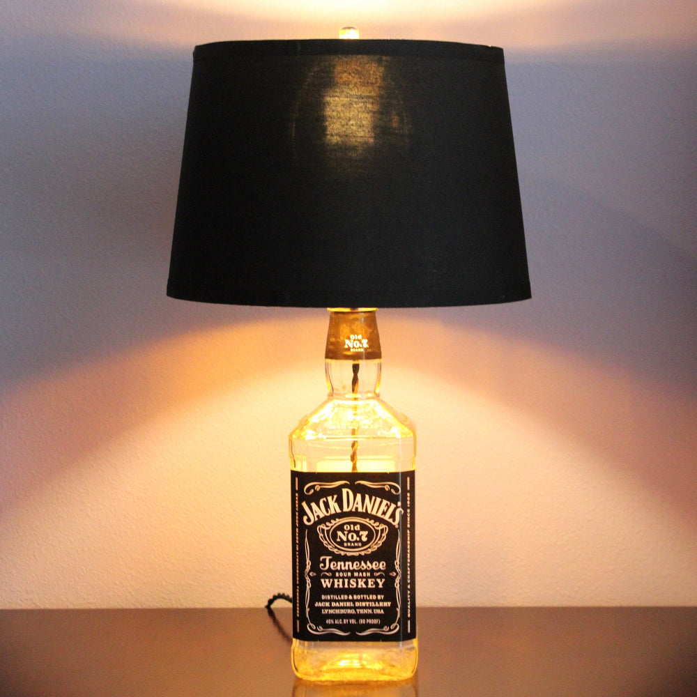 Jack Daniel's whiskey bottle repurposed as a lamp with a black shade.