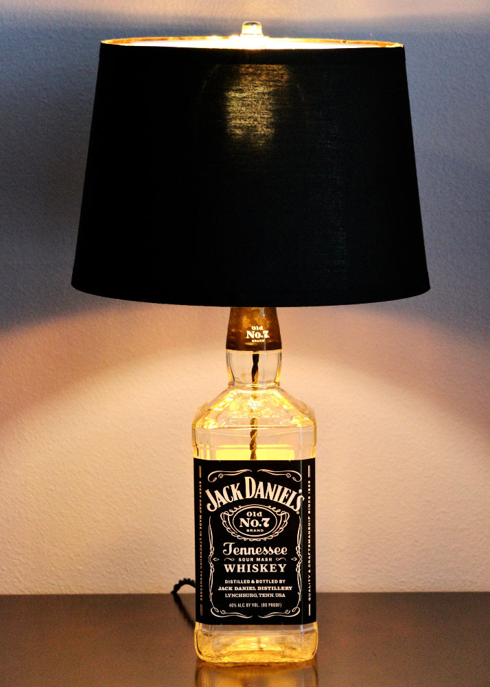 Jack Daniel's whiskey bottle repurposed as a lamp with a black shade.