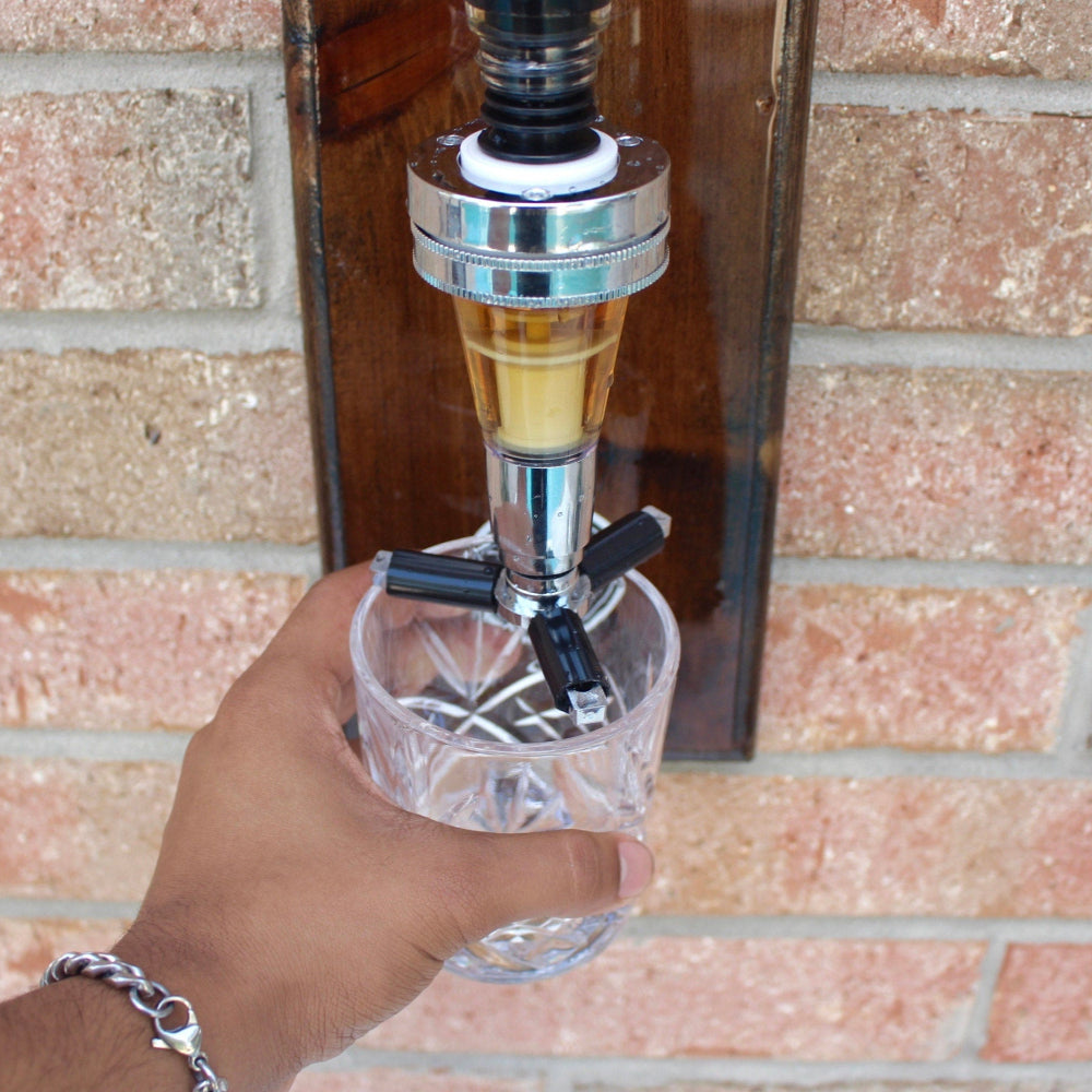 Hand holding a glass under a beer tap against a brick wall.