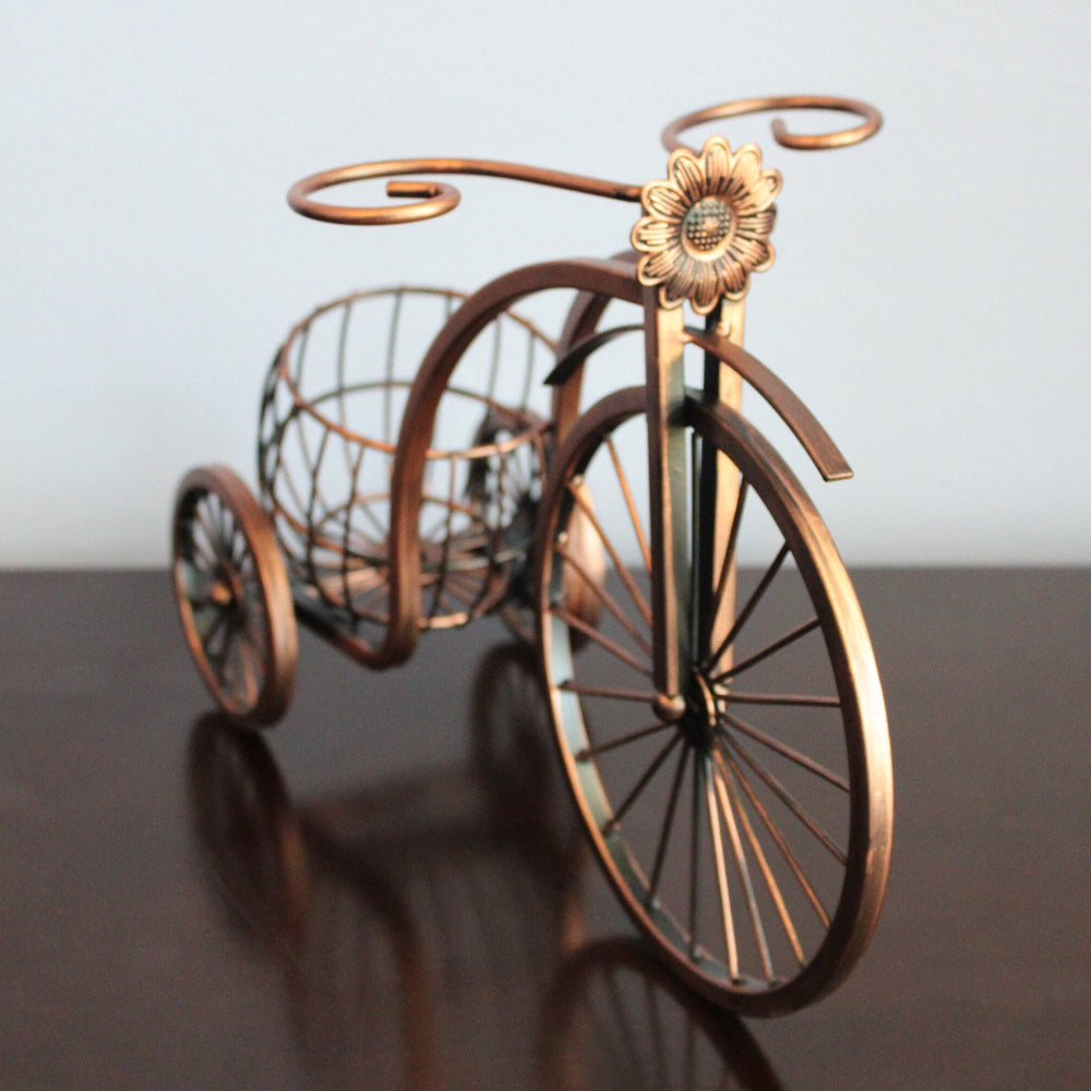 Decorative bronze bicycle with a basket on a reflective surface