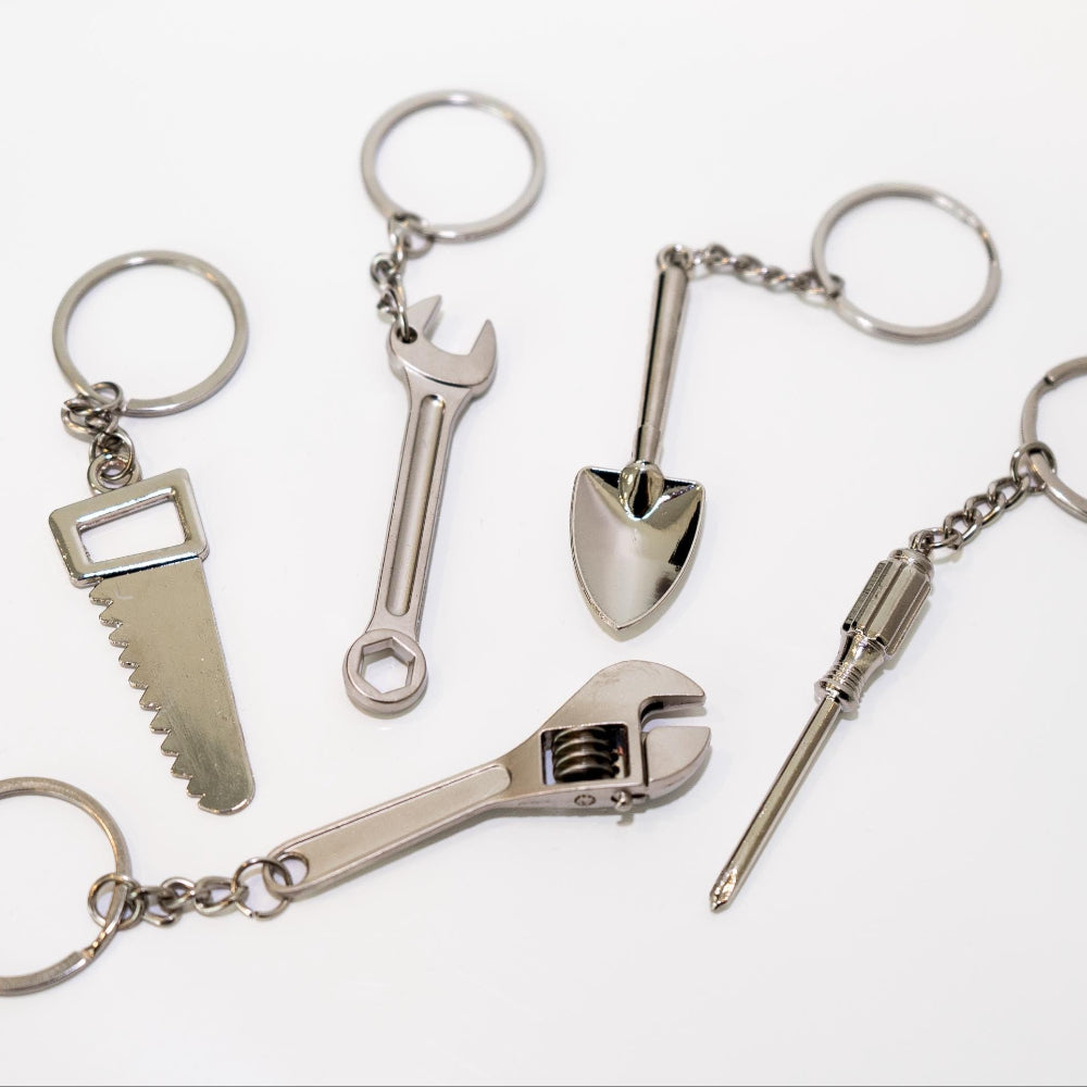 Set of metal keychains shaped like tools on a white background