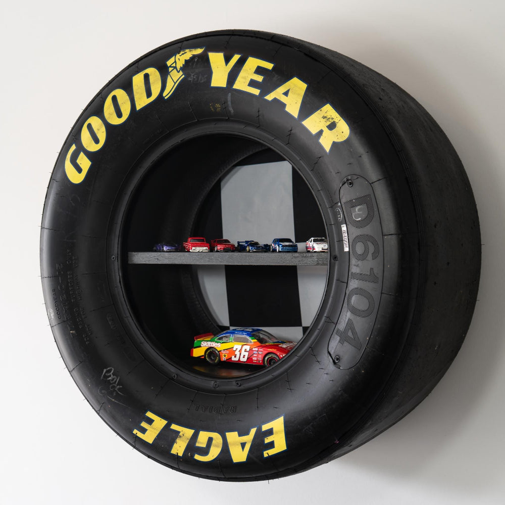 Goodyear tire with shelf inside displaying small model cars on a white background