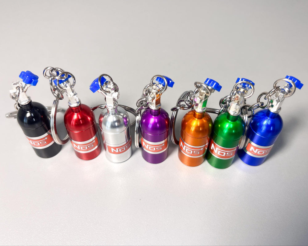 Set of colorful keychains shaped like small gas canisters on a light gray background