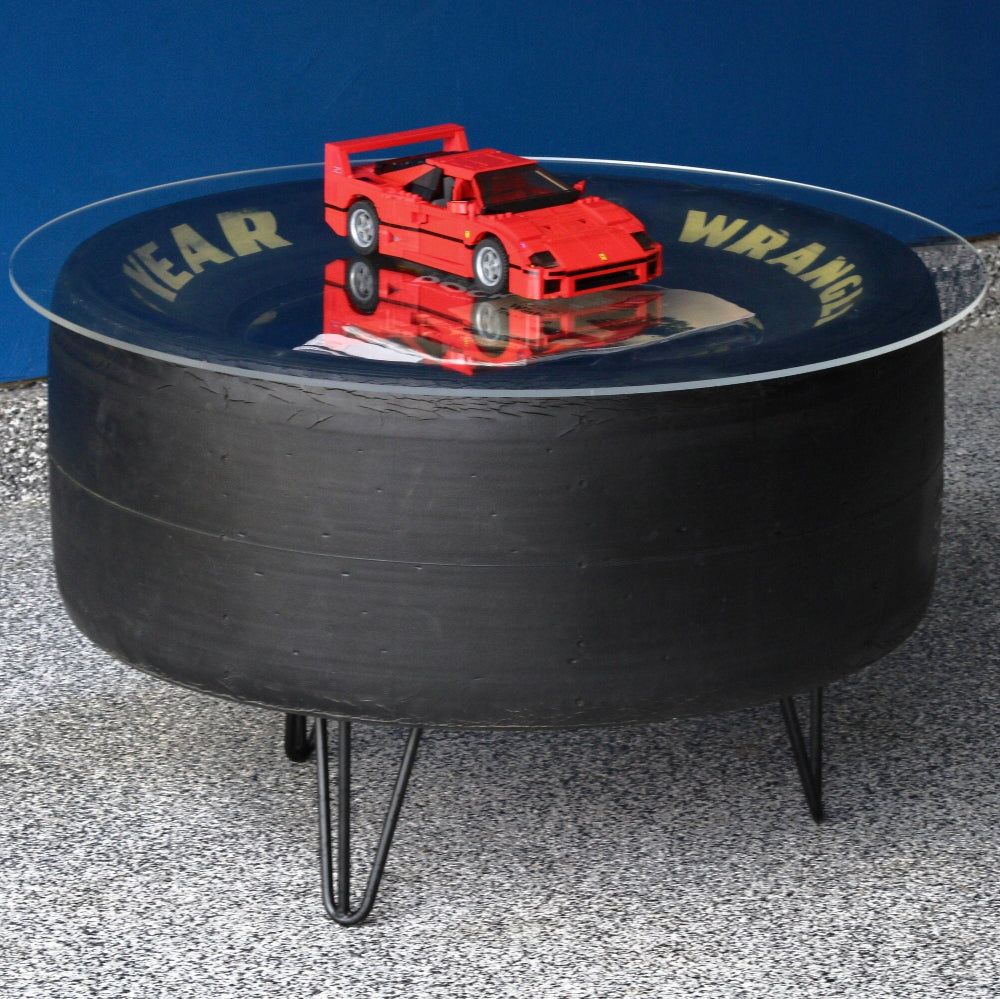 Round black table with a red toy car on a reflective surface against a blue wall.