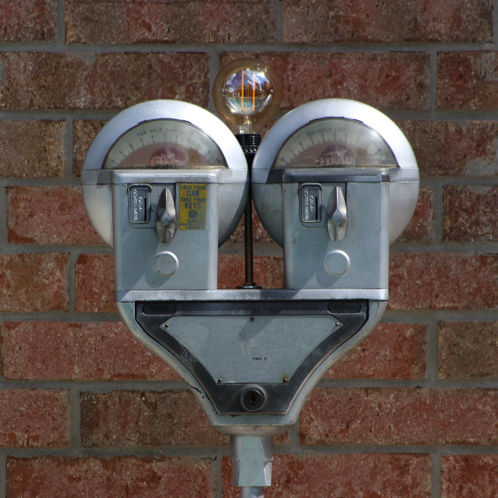 Vintage parking meter with a light bulb on a brick wall
