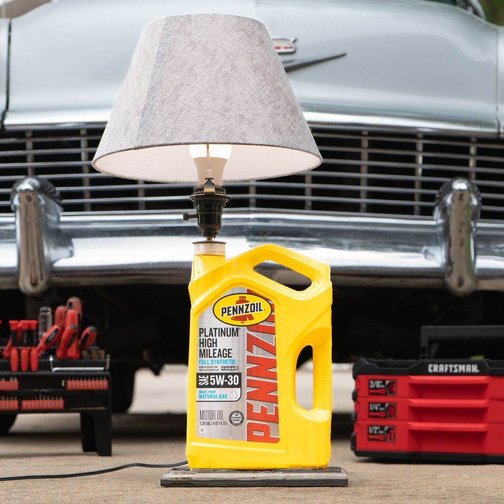 Penny's oil bottle with tools and a lamp in front of a classic car