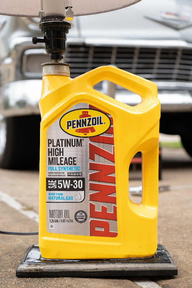 Pennzoil motor oil container on a stand with a car in the background