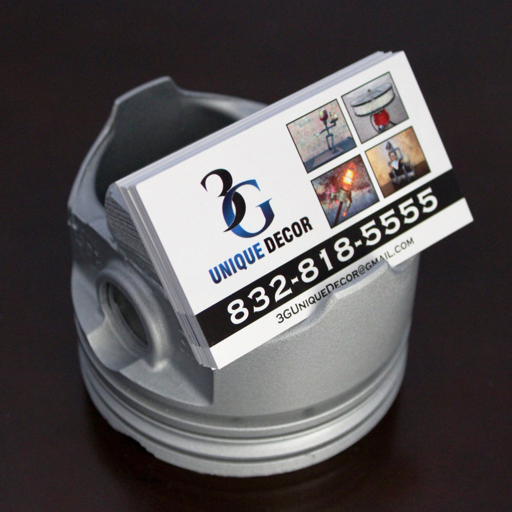 Business card with '3G Unique Decor' on a metallic object against a dark background