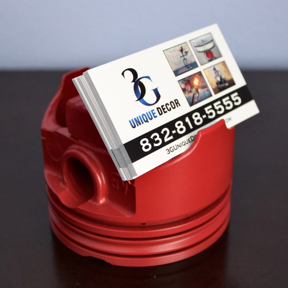Red business card holder with a business card featuring contact information on a dark surface.
