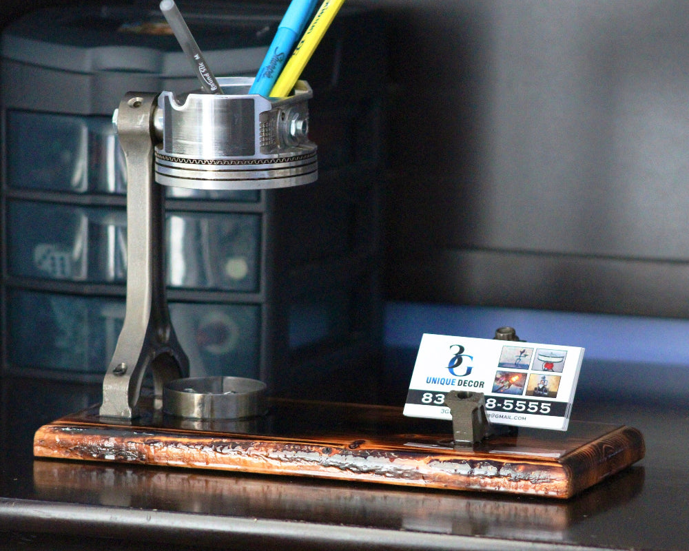 Desk organizer with cylindrical container, pen holder, and business card stand on a reflective surface.