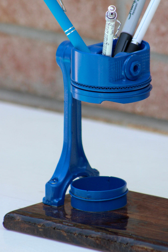 Blue pen holder with stationery items on a wooden surface
