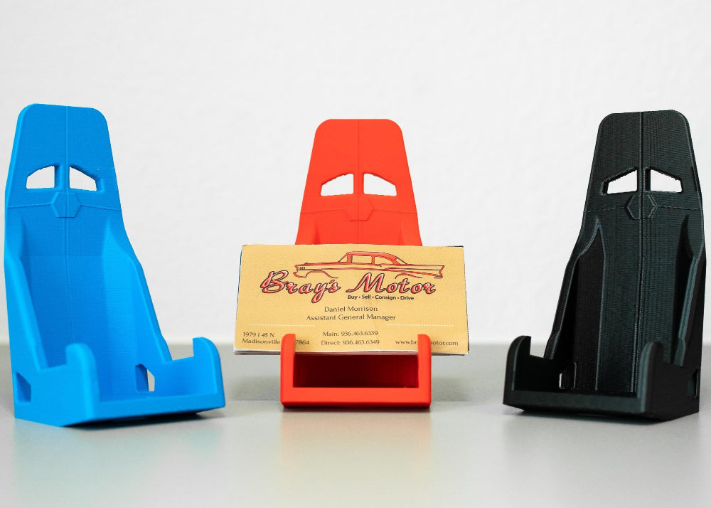 Three colorful car seat-shaped business card holders on a white background