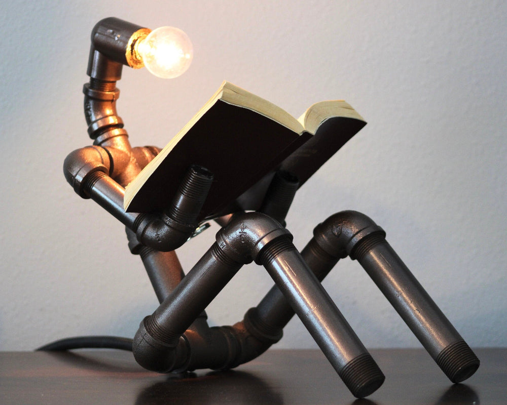Lamp made from pipes and a book with a light bulb inside on a plain background
