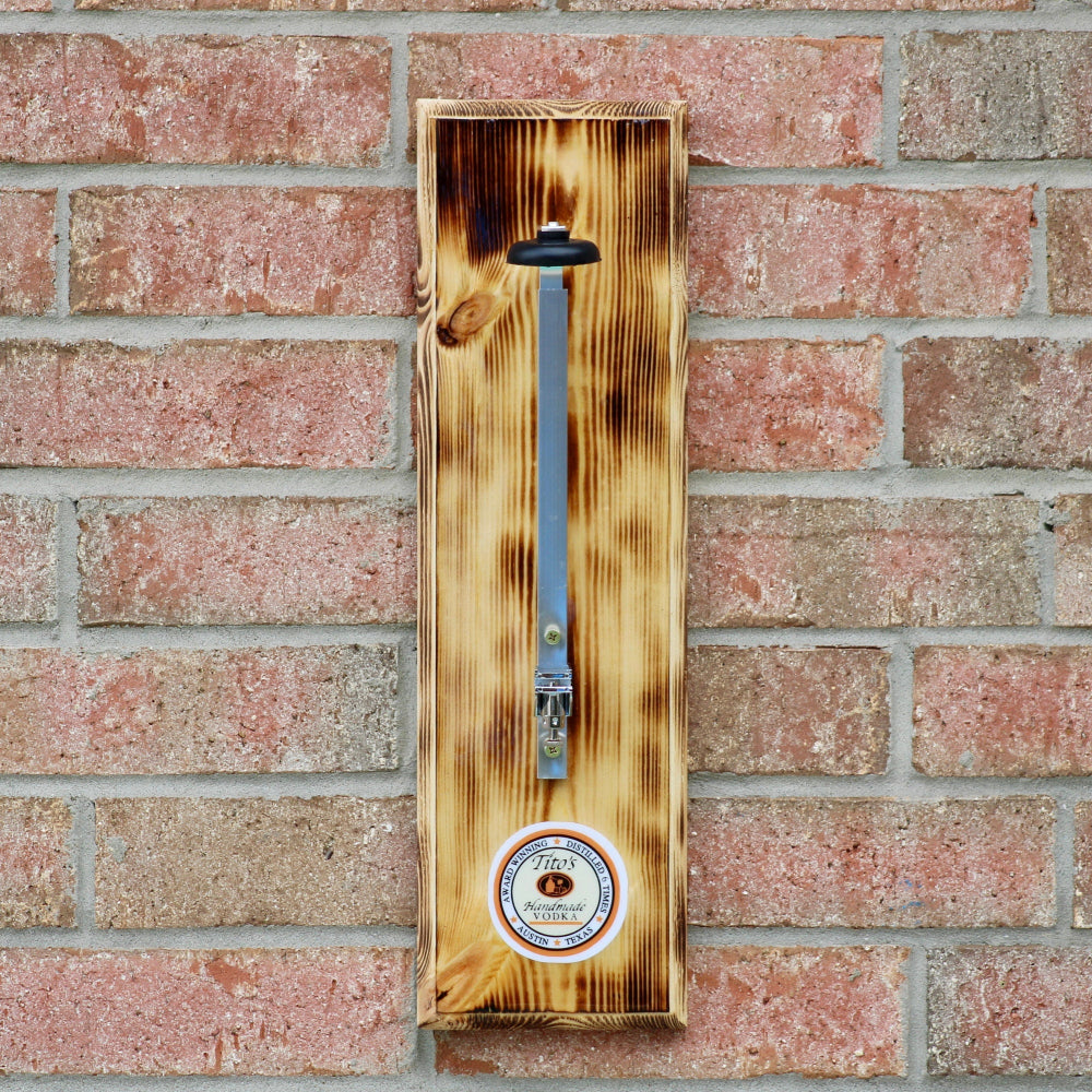 Wooden thermometer with a circular design on a brick wall