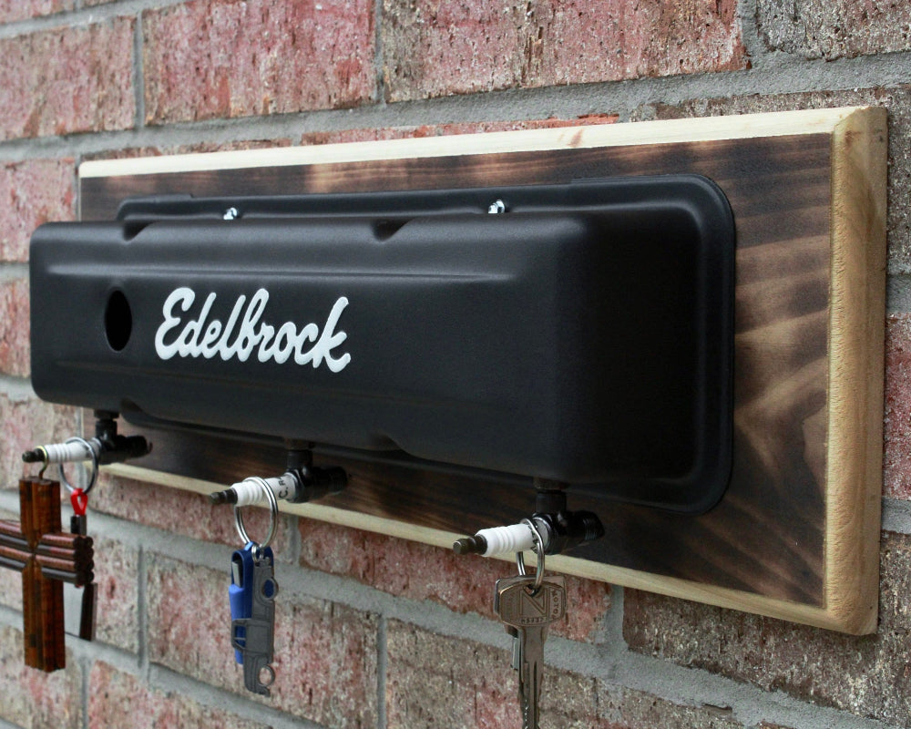 Key holder with 'Edelbrock' branding attached to a brick wall.