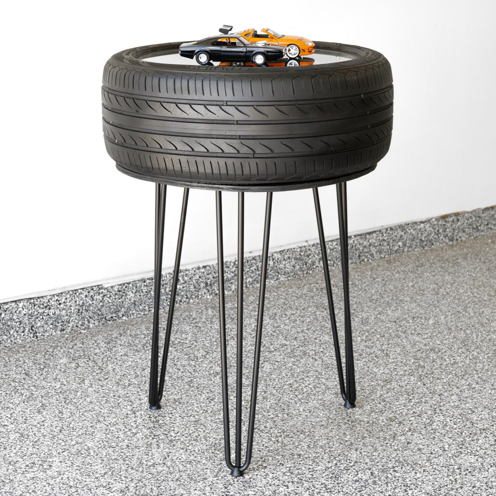 Side table made from a tire with hairpin legs on a concrete floor.