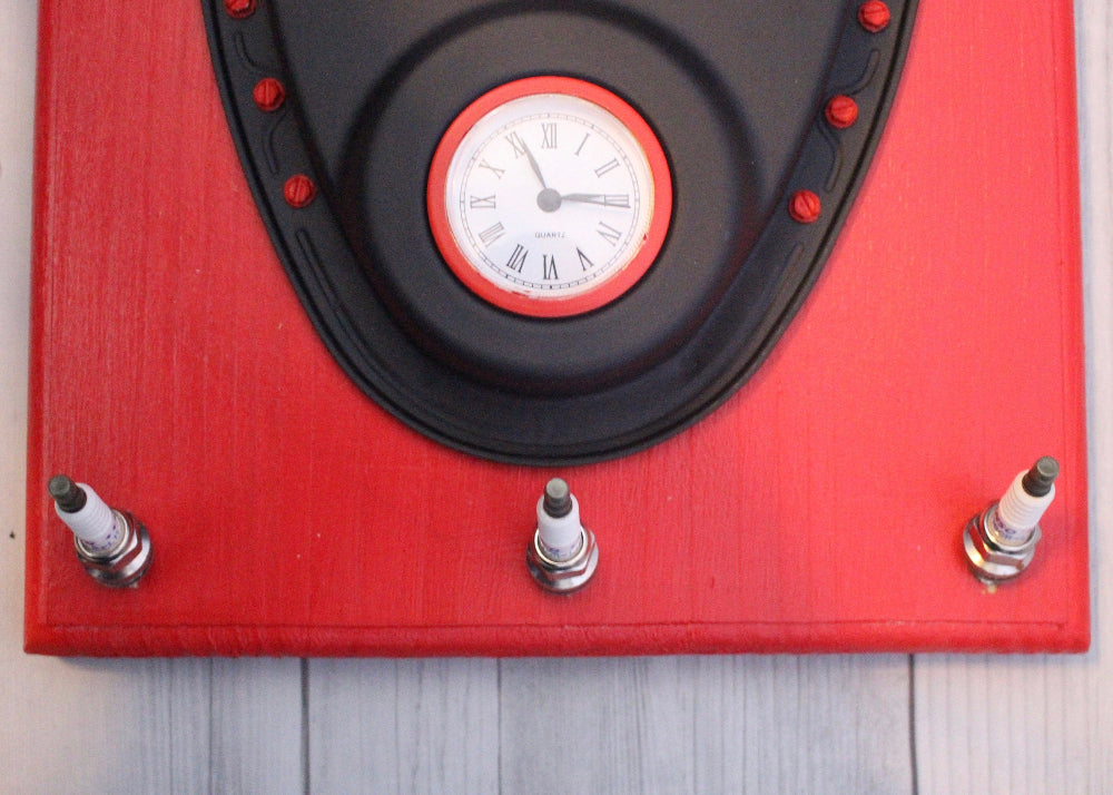 Red clock with black border and white face on a wooden surface