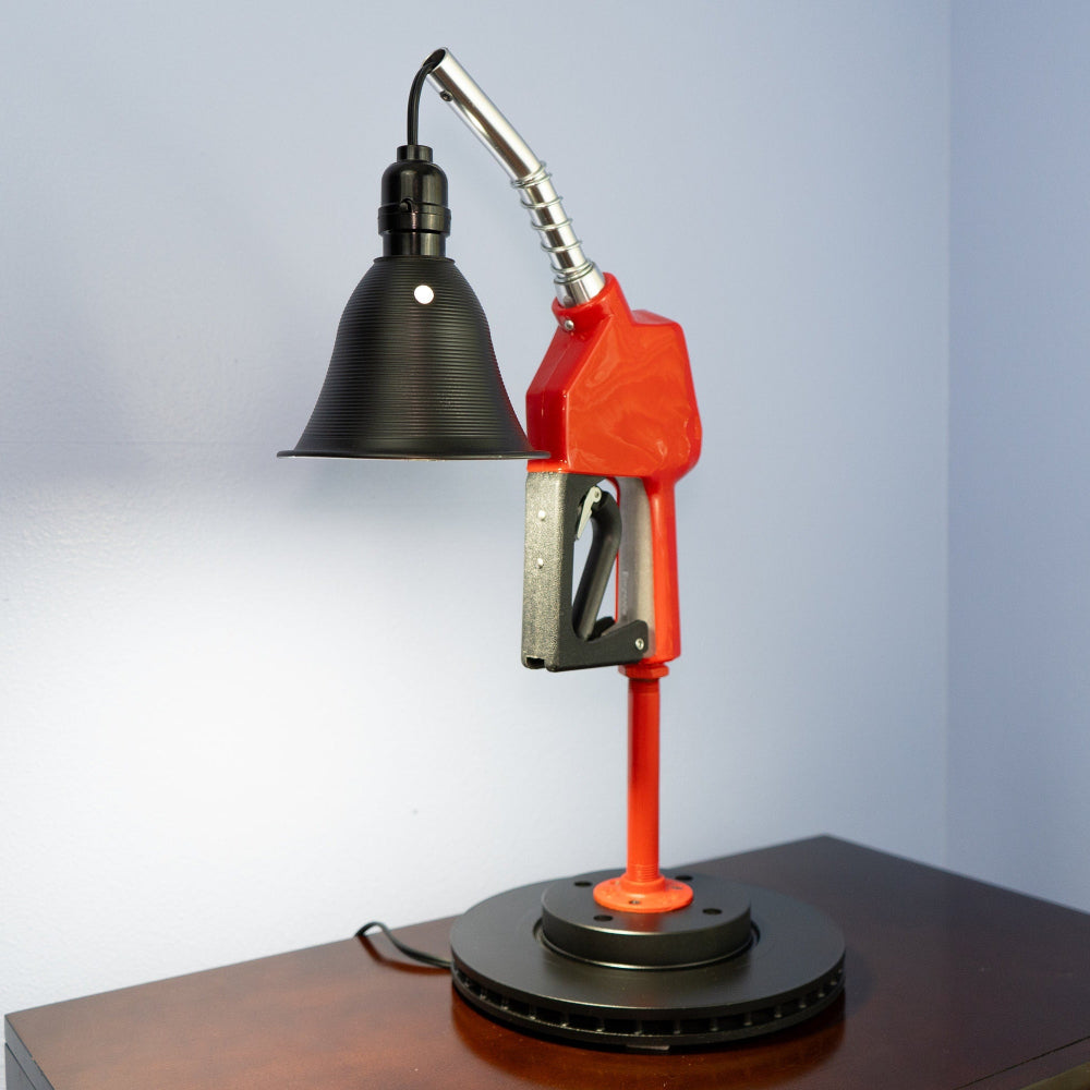 Table lamp designed like a vintage gas pump on a wooden surface with a light blue background