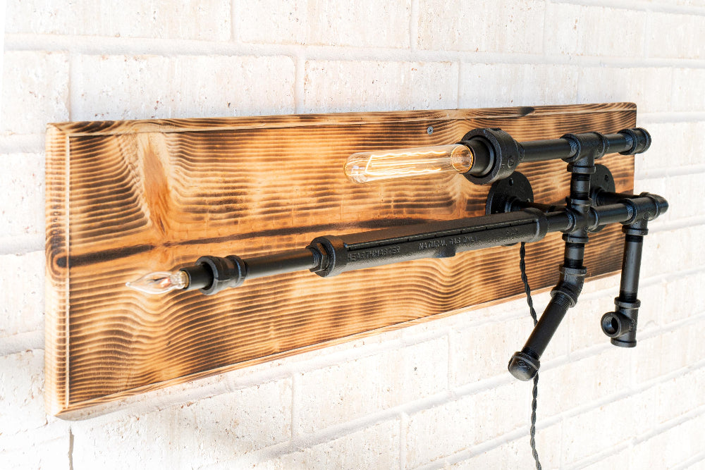 Wall-mounted decorative item with wooden panel and black metal pipes on a white brick wall background