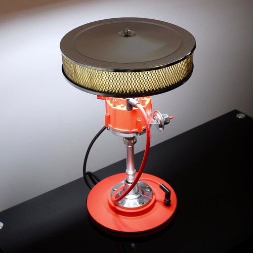 Red and silver mechanical device on a black surface with a gray background