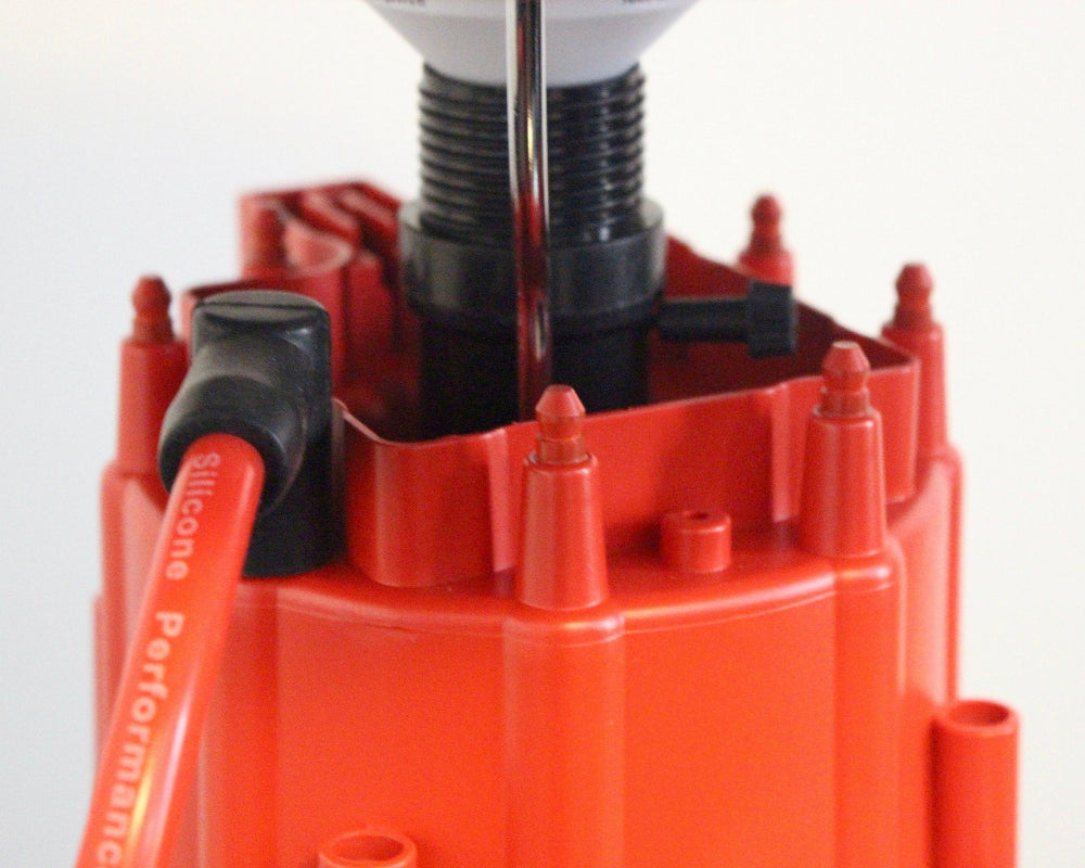 Close-up of a red ignition distributor with black wiring on a white background