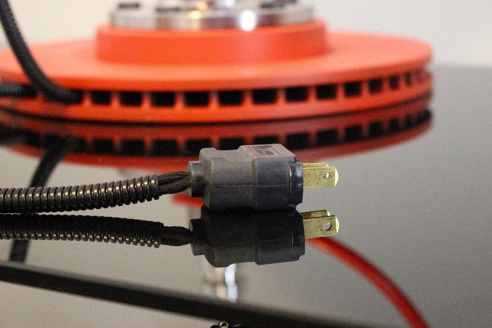 Electrical plug with red and black wires against a blurred background