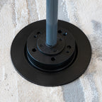 Black metal base with a gray pole on a textured surface