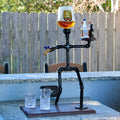 Skeletan-like figure with a glass of beer on a table outdoors