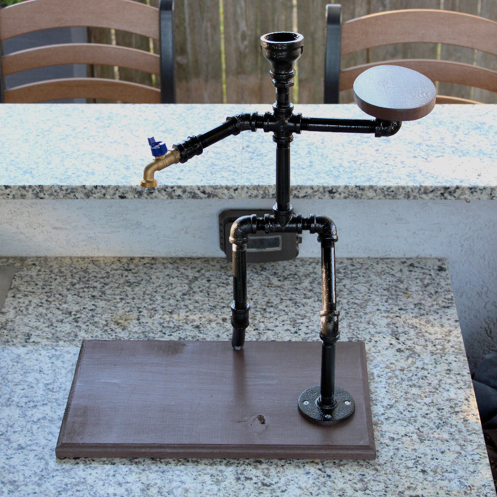 Decorative candle holder made from black metal pipes on a wooden base outdoors.
